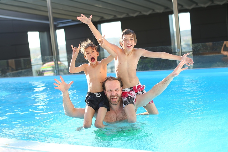 Zdjęcie przedstawia mężczyznę z dwójką dzieci w basenie.