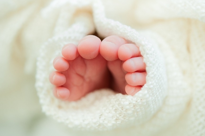 Zdjęcie przedstawia stópki noworodka zawinięte w biały ręcznik.