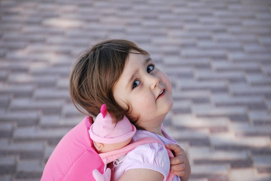 Dziewczynka z różowym plecakiem spoglądająca w kierunku osoby robiącej zdjęcie