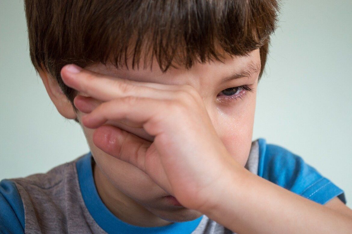 Zapłakany chłopiec przecierający ręką oko