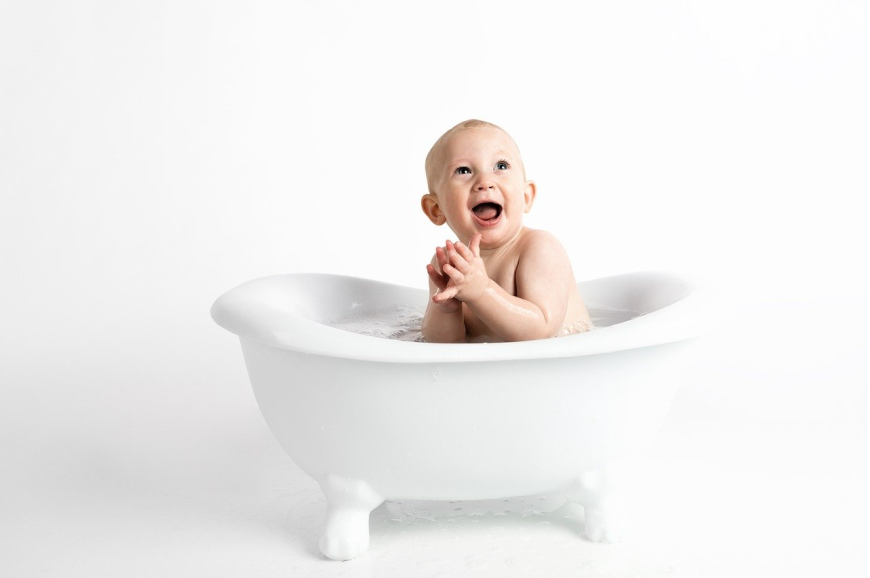 Uśmiechnięty niemowlak w malutkiej wannie.